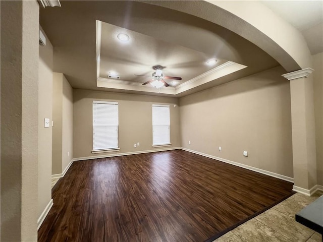 spare room with ornate columns, a raised ceiling, a ceiling fan, and wood finished floors