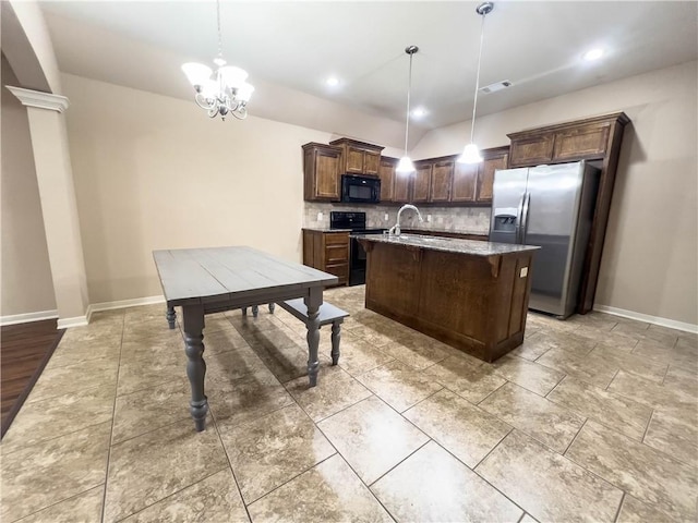 kitchen with a center island with sink, appliances with stainless steel finishes, light stone countertops, pendant lighting, and backsplash