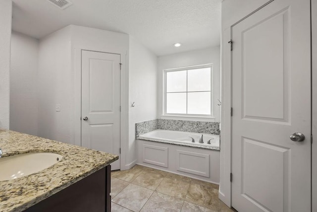 bathroom featuring a bath, tile patterned flooring, a textured ceiling, and vanity