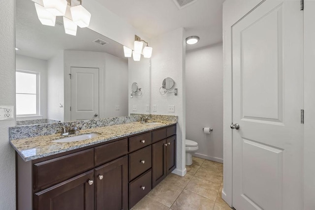 bathroom with visible vents, double vanity, a sink, and toilet