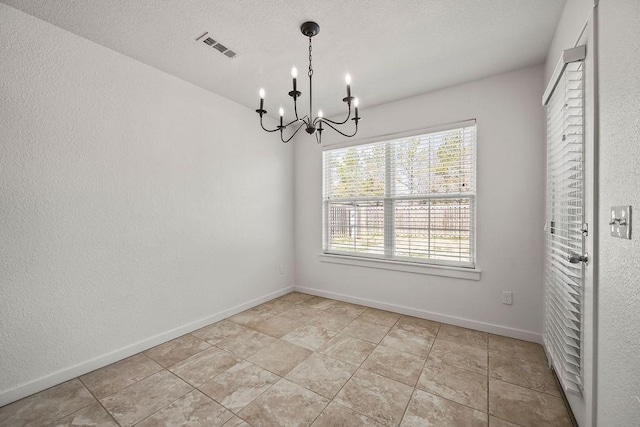 interior space with a textured ceiling, an inviting chandelier, visible vents, and baseboards