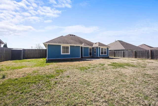 back of house with a yard and a fenced backyard