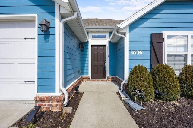 property entrance featuring a garage and a shingled roof