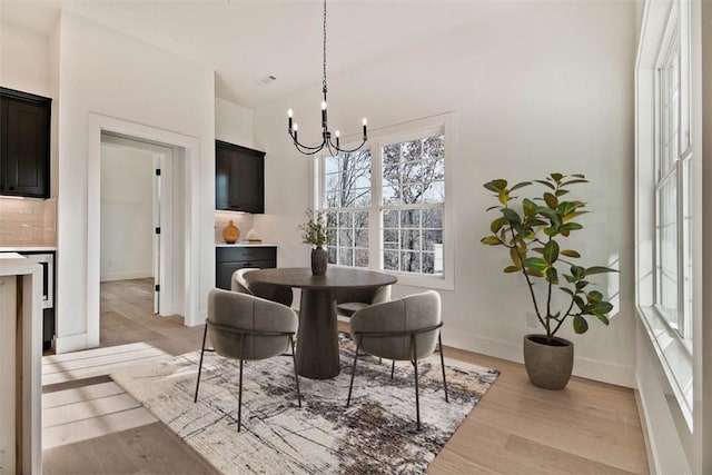 dining space featuring light wood-style floors, a chandelier, and baseboards