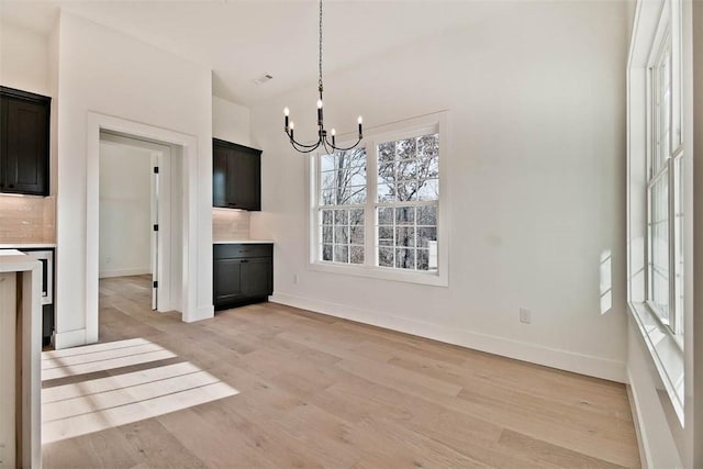 unfurnished dining area with light wood finished floors, baseboards, and a chandelier