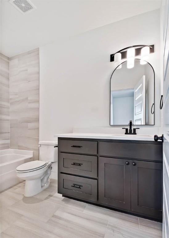 full bathroom with toilet, vanity, and visible vents