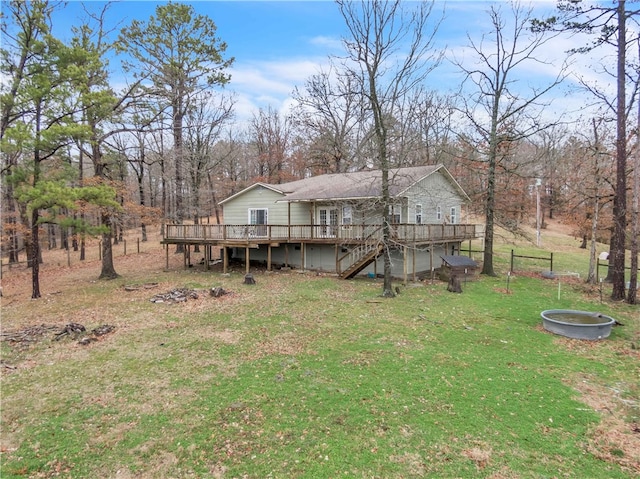 rear view of house featuring a deck, stairway, and a lawn