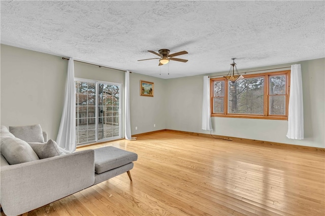 unfurnished living room featuring ceiling fan, a textured ceiling, baseboards, and hardwood / wood-style floors