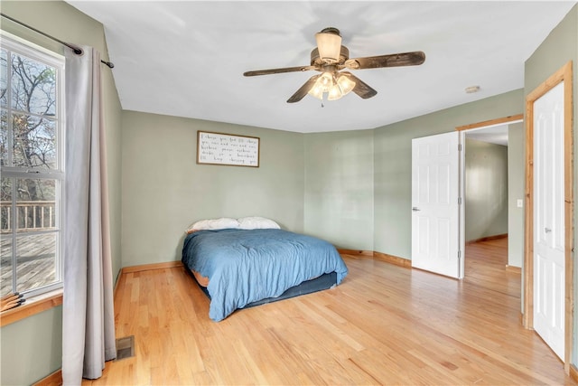 bedroom featuring light wood-style floors, baseboards, visible vents, and a ceiling fan