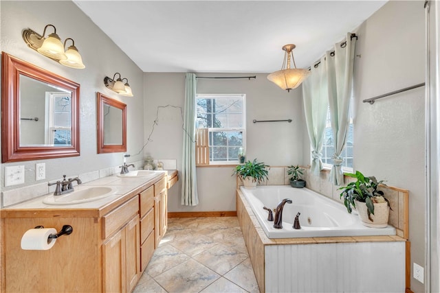 bathroom featuring double vanity, a tub with jets, a sink, and baseboards