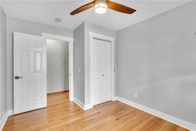 unfurnished bedroom featuring light wood-type flooring, ceiling fan, baseboards, and a closet