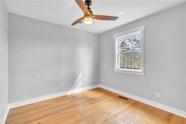 spare room featuring hardwood / wood-style flooring, baseboards, visible vents, and ceiling fan