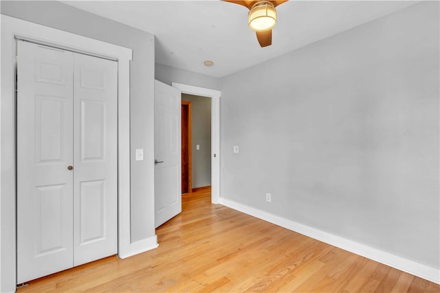 unfurnished bedroom with a ceiling fan, a closet, light wood-style flooring, and baseboards