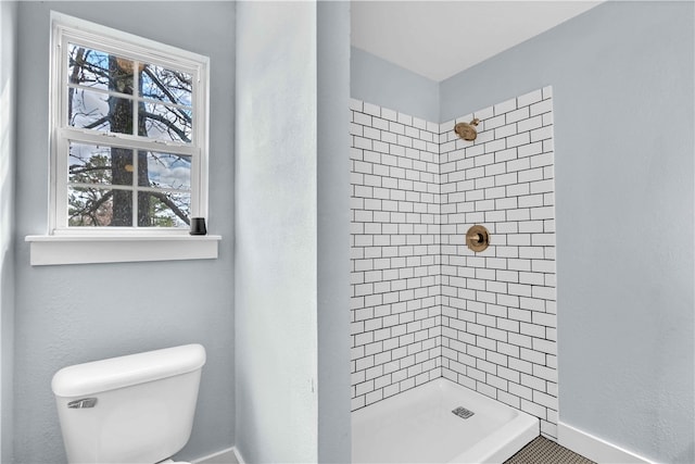 bathroom featuring toilet, a stall shower, baseboards, and a healthy amount of sunlight