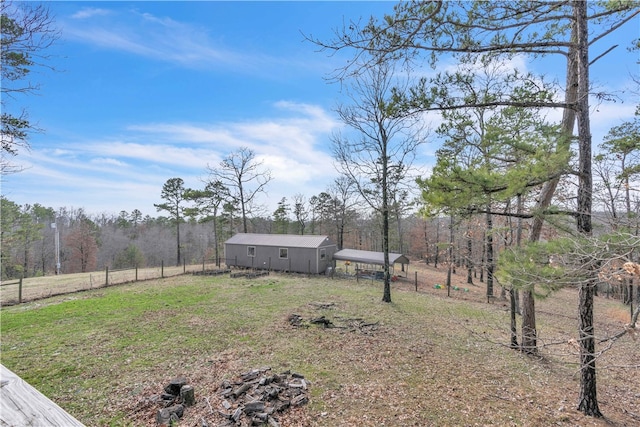 view of yard featuring an outdoor structure, fence, and a view of trees