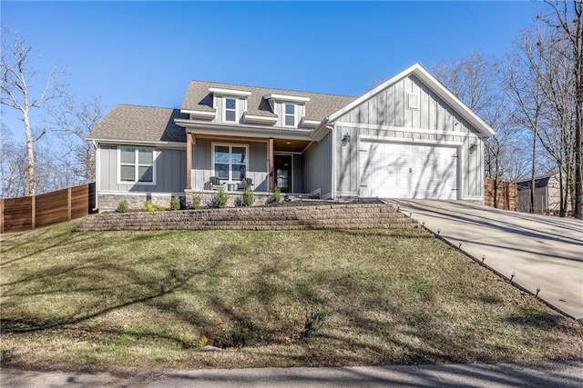 view of front of house with a garage, a shingled roof, stone siding, fence, and board and batten siding