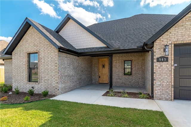 view of front facade featuring a shingled roof, brick siding, an attached garage, and a front lawn