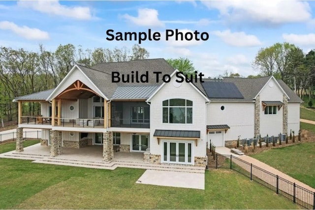 rear view of house featuring a standing seam roof, a patio area, a lawn, and roof mounted solar panels