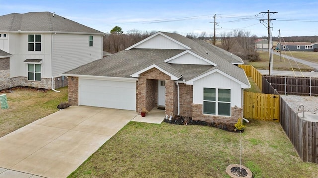 view of front of home with concrete driveway, roof with shingles, an attached garage, fence, and a front lawn