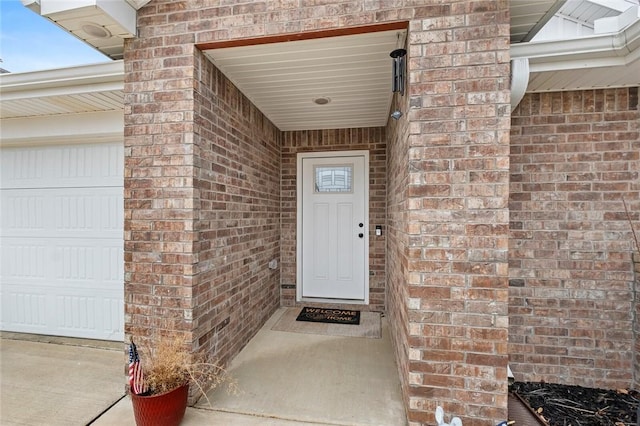 doorway to property with a garage and brick siding