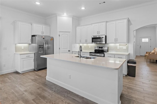 kitchen with arched walkways, stainless steel appliances, a sink, visible vents, and white cabinets