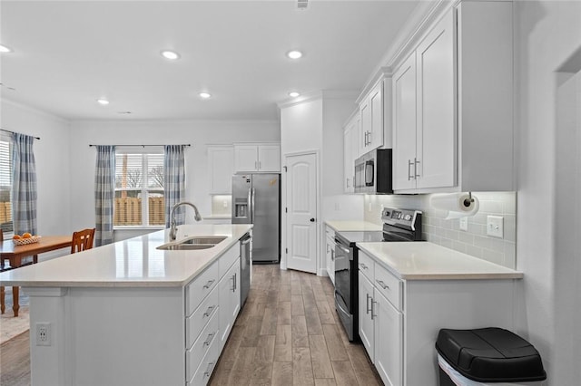 kitchen with wood finished floors, a sink, light countertops, appliances with stainless steel finishes, and decorative backsplash