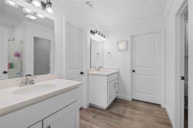 full bathroom featuring wood finished floors, ornamental molding, a sink, and visible vents