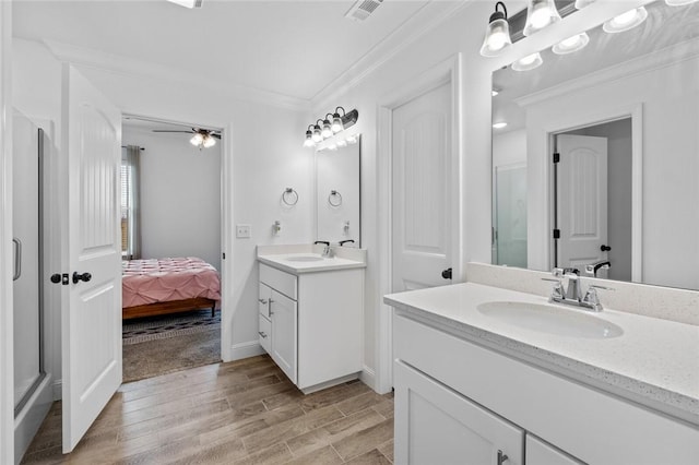 bathroom with ornamental molding, visible vents, a sink, and wood finished floors