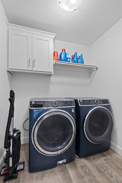 washroom featuring wood tiled floor, cabinet space, baseboards, and separate washer and dryer