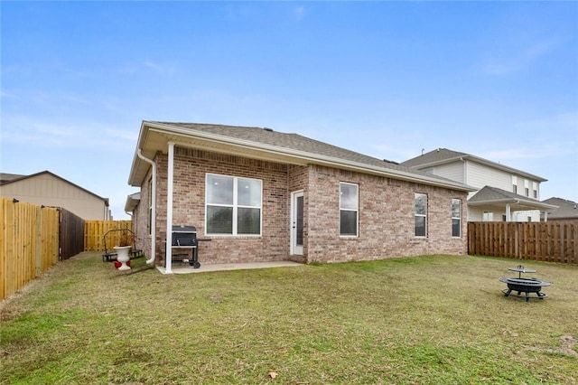 rear view of house featuring an outdoor fire pit, brick siding, a lawn, and a fenced backyard