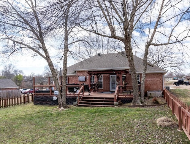 back of house with fence private yard, brick siding, a yard, and a deck