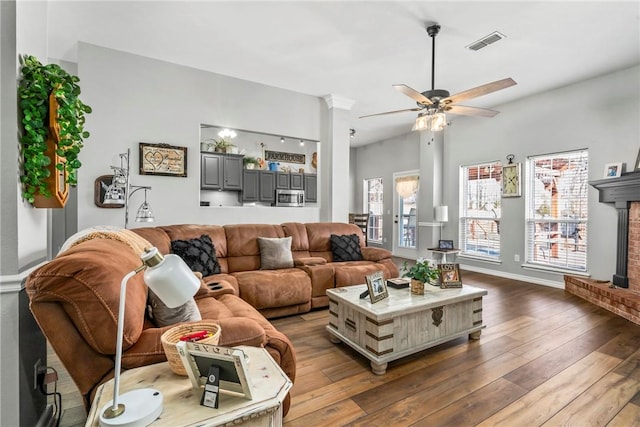 living area featuring hardwood / wood-style flooring, a fireplace, visible vents, and a ceiling fan