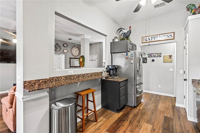 kitchen with dark stone countertops, visible vents, dark wood finished floors, and a ceiling fan