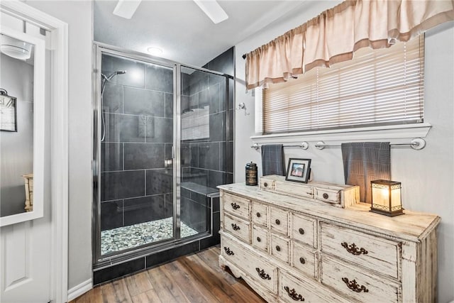 bathroom with wood finished floors and a shower stall