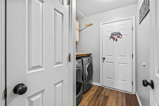 laundry room with dark wood-type flooring, washing machine and dryer, cabinet space, and baseboards