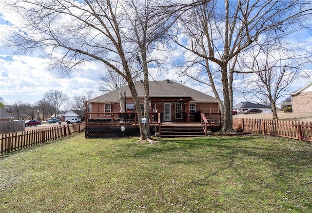 rear view of property featuring brick siding, a lawn, a fenced backyard, and a wooden deck