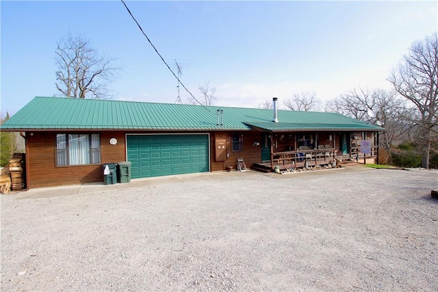 view of front facade featuring metal roof, driveway, a porch, and an attached garage