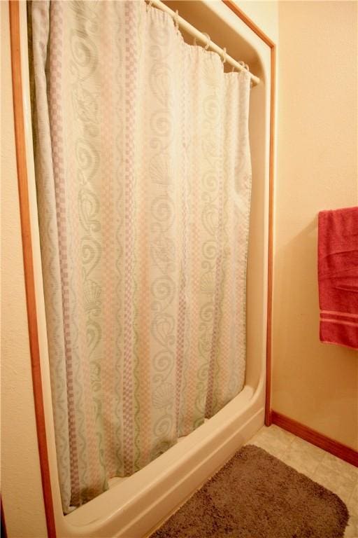 full bath featuring curtained shower and baseboards