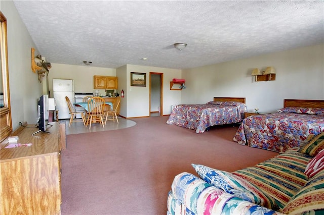 bedroom featuring freestanding refrigerator, a textured ceiling, and carpet