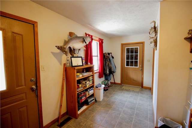 foyer featuring a textured ceiling and baseboards