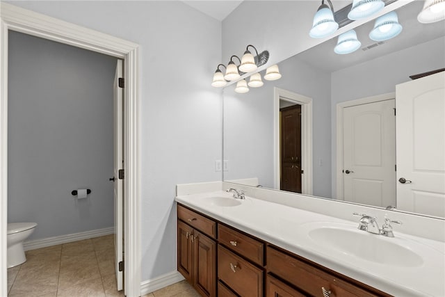 bathroom with a sink, toilet, double vanity, and tile patterned flooring