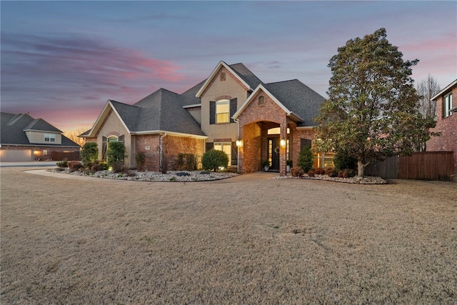 traditional-style home featuring brick siding, a shingled roof, and fence