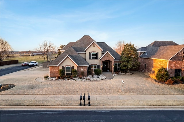 view of front facade featuring brick siding, driveway, and roof with shingles