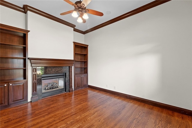 unfurnished living room with wood finished floors, a glass covered fireplace, crown molding, baseboards, and ceiling fan