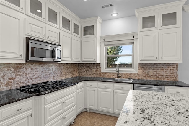 kitchen with visible vents, a sink, stainless steel appliances, light tile patterned floors, and decorative backsplash