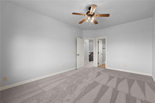 spare room with ceiling fan, baseboards, and light carpet