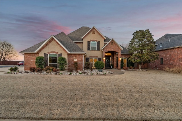 view of front of house with brick siding, a front yard, and roof with shingles