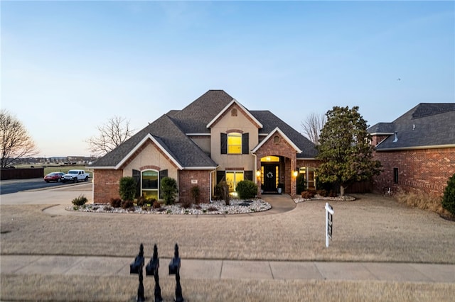 traditional-style home featuring brick siding and a shingled roof