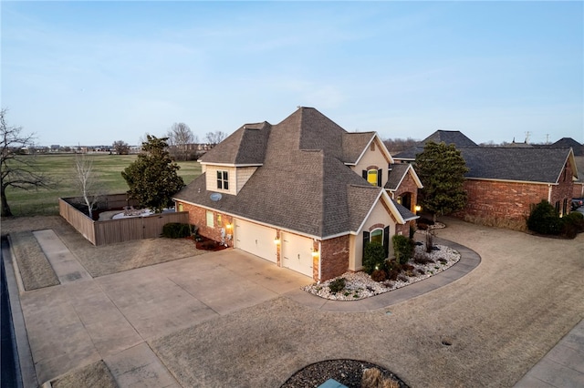 view of property exterior with concrete driveway, fence, brick siding, and roof with shingles