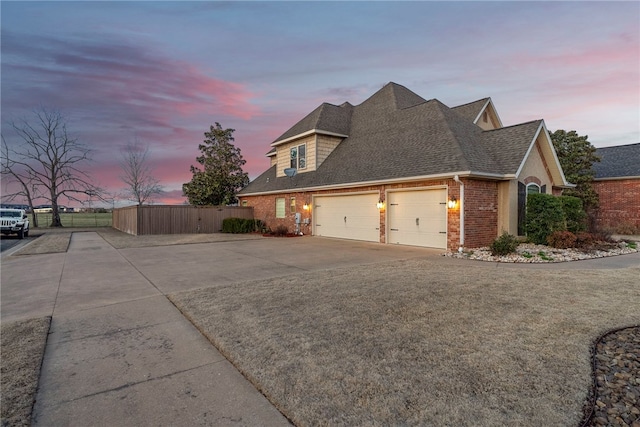 view of home's exterior with fence, roof with shingles, concrete driveway, an attached garage, and brick siding